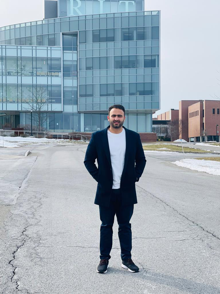 person standing outside in front of a glass building.