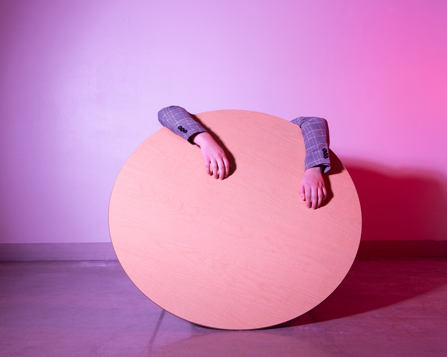 A turned-over table with a person's arms and hands hanging over it.