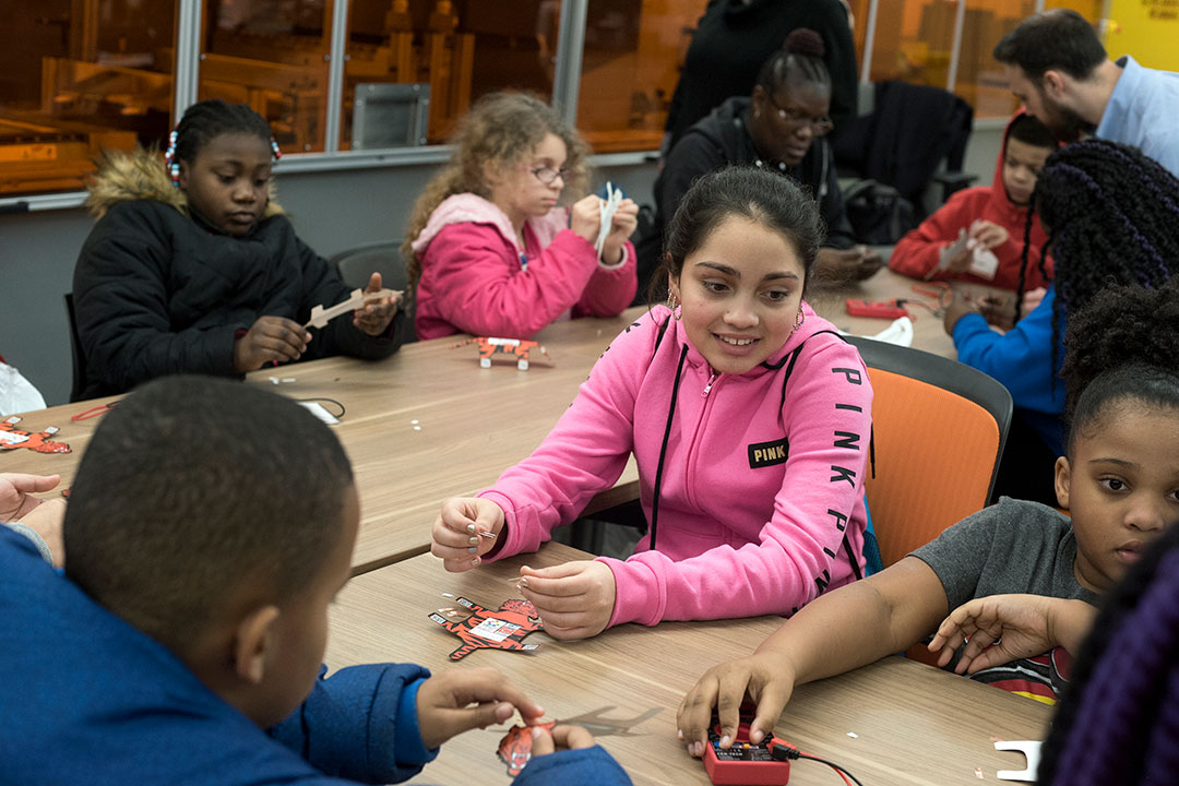 Elementary school students sit at table.