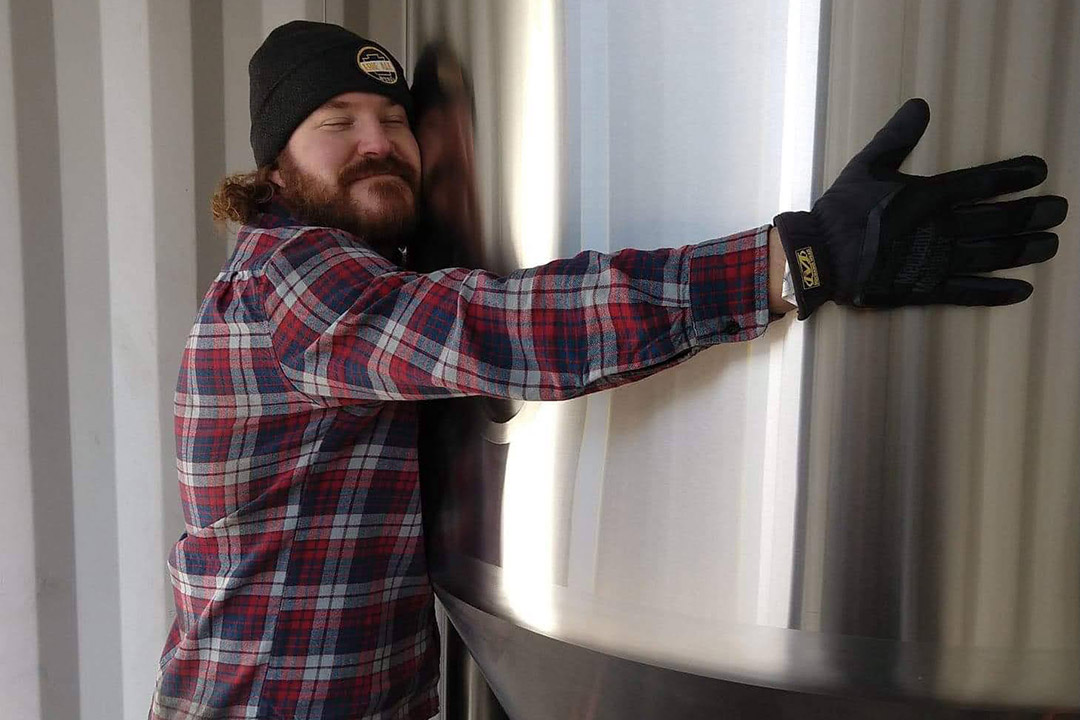 man hugging vat of beer.