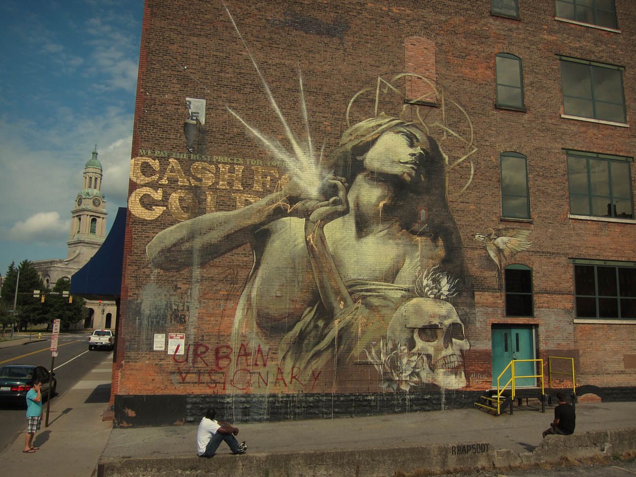 A large building mural feature a woman and a skull.