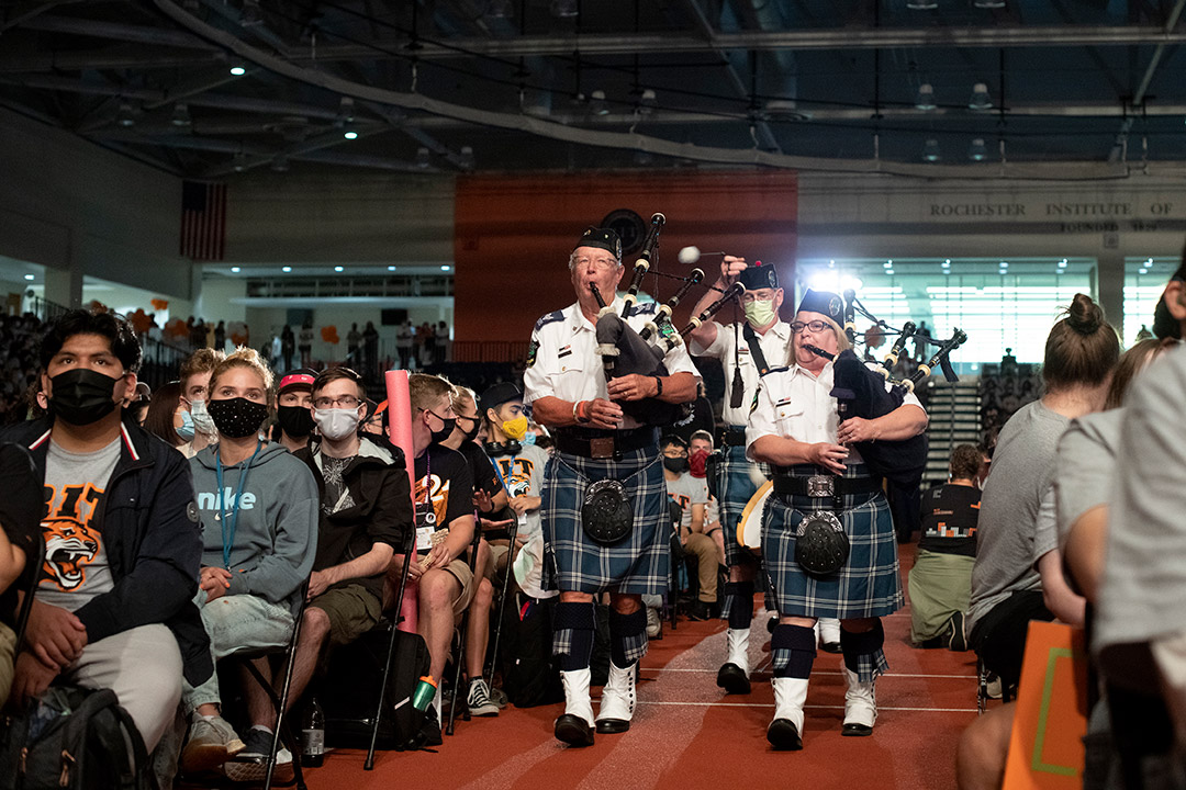 people playing bagpipes processing into the field house.