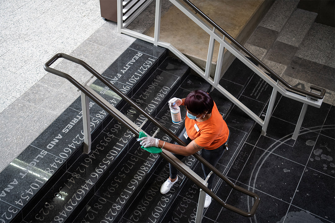 custodian cleaning stairway railing.