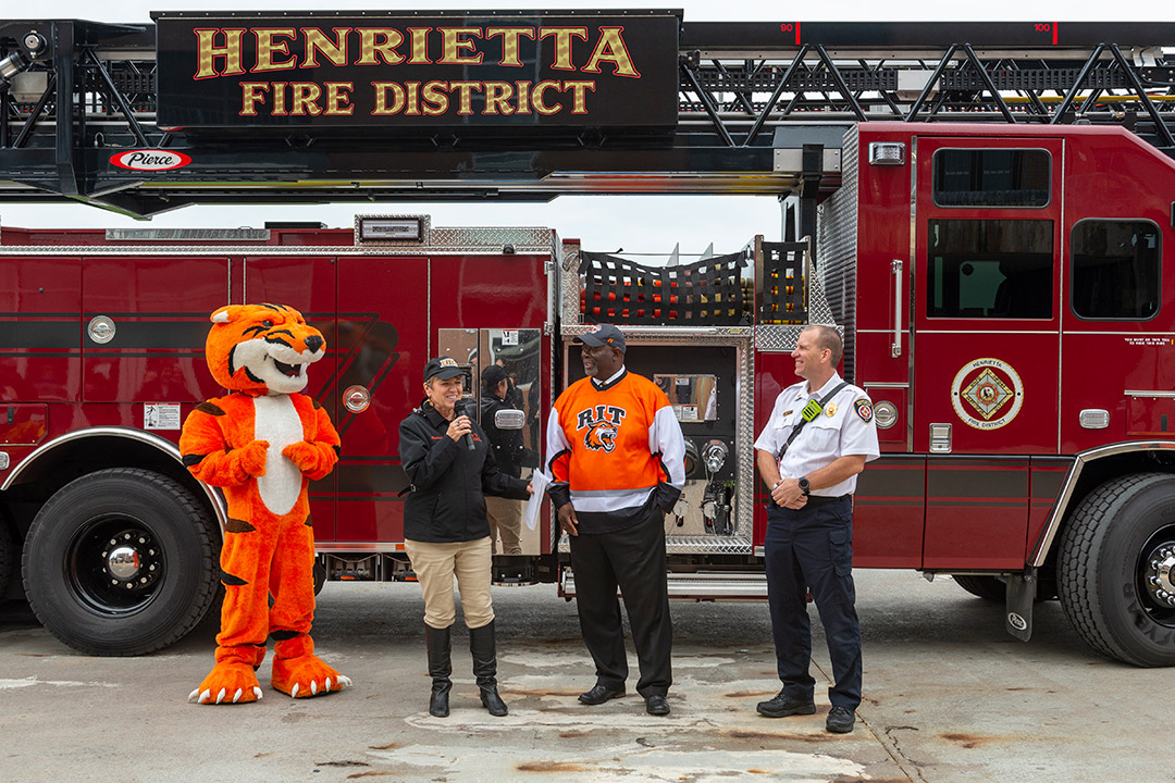 People stand in front of firetruck.