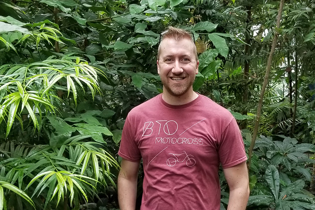 Fred Oettinger outside with foliage in the background.