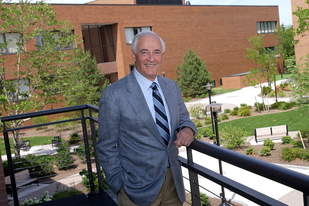 man posing on balcony overlooking brick building.