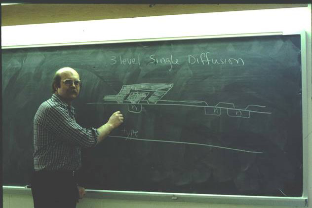 professor writing on chalkboard in the 1970s.