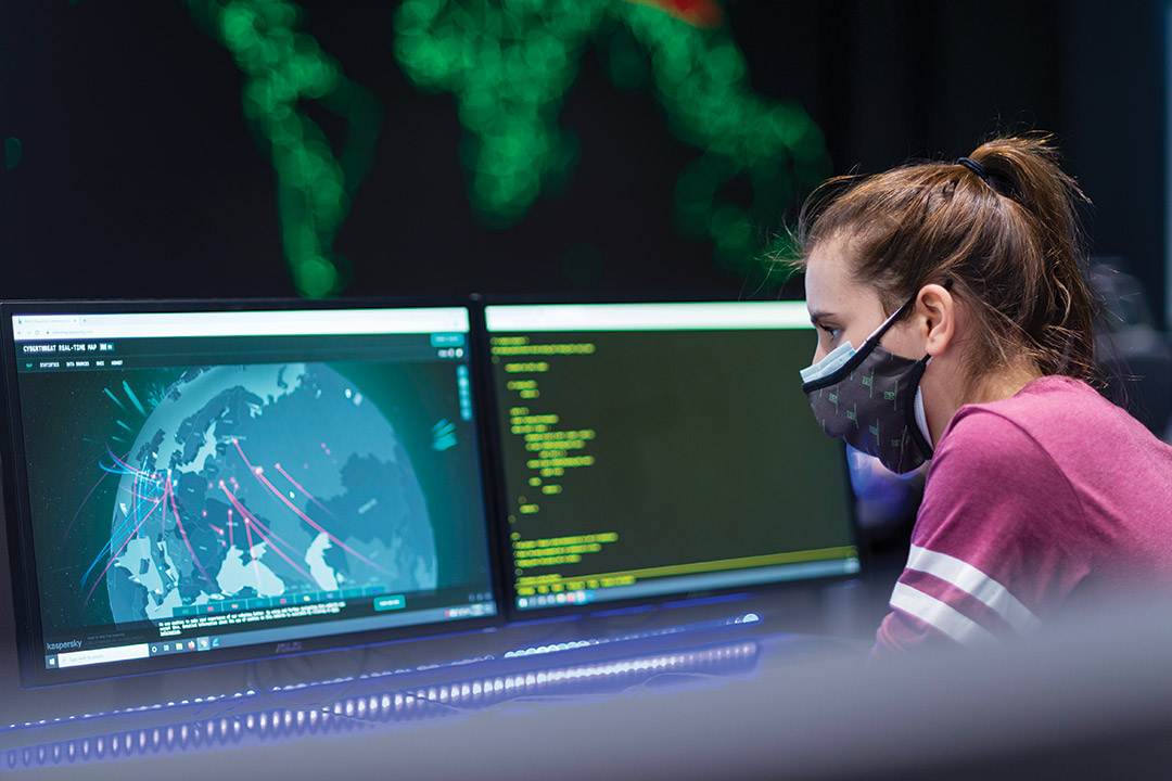 student wearing mask looking at two computer screens.