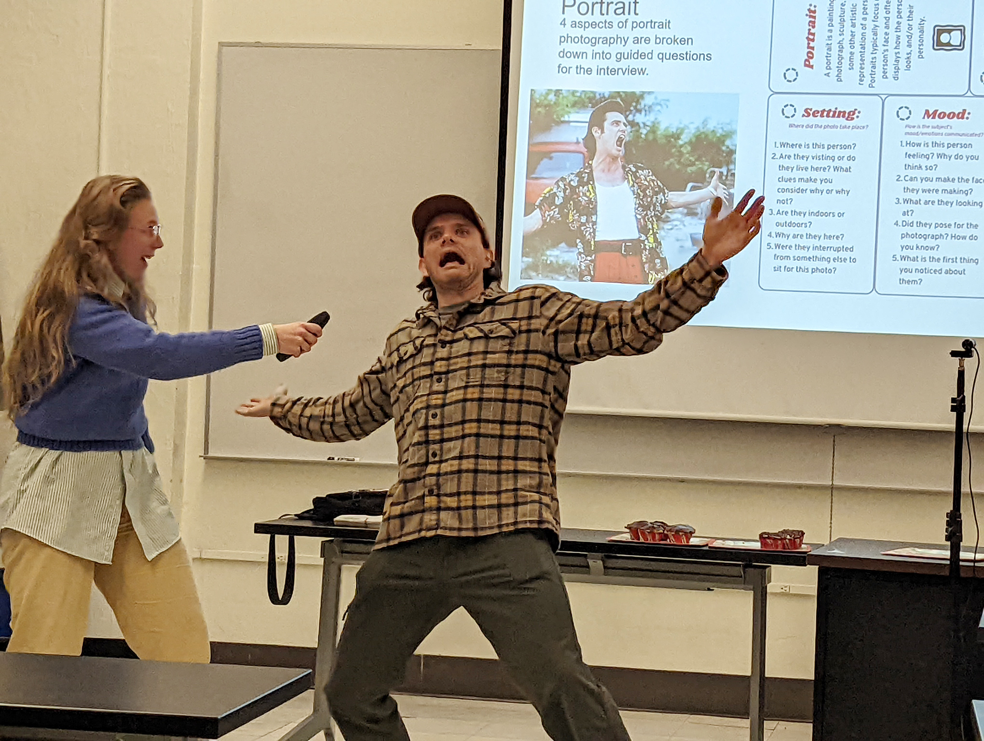 Two students give a presentation with animated looks on their faces.