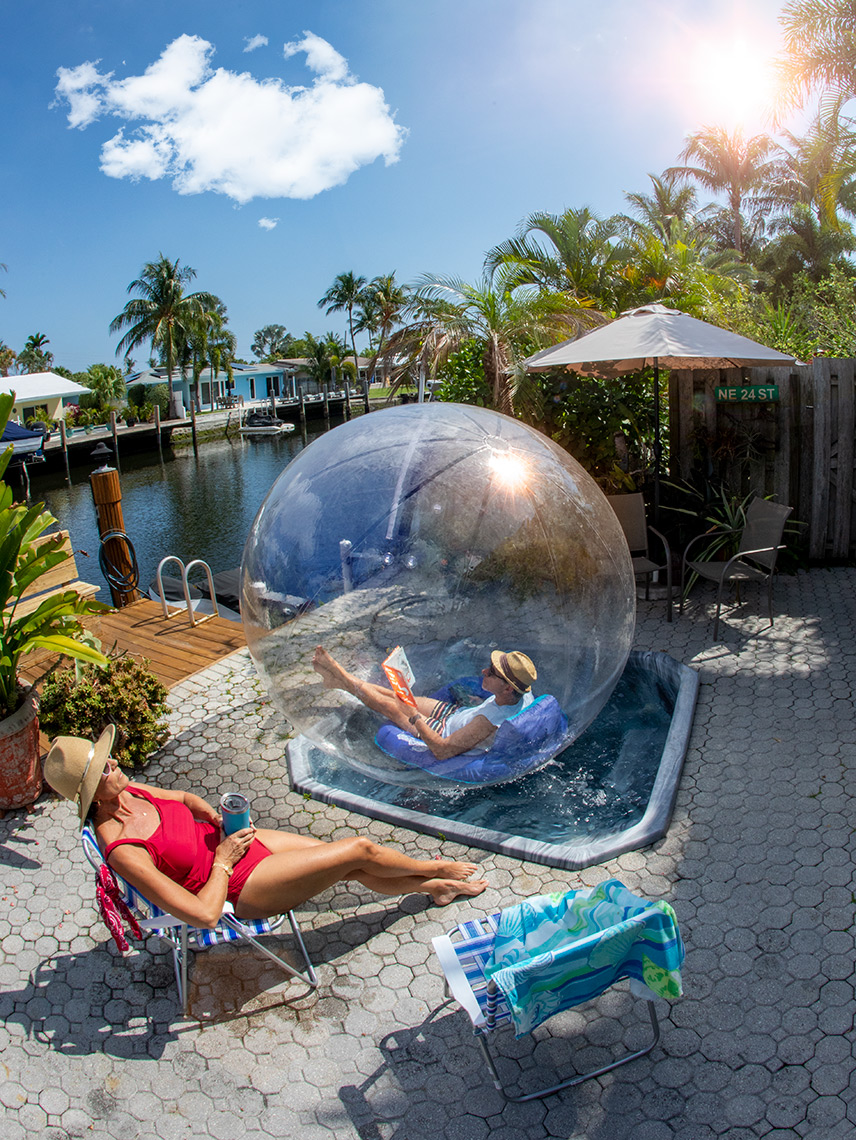 George Kamper lounges in his bubble in jacuzzi while his wife sits on a chair outside of it.