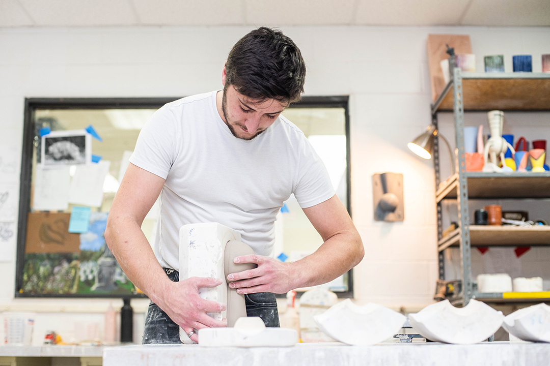 A student handles pottery.