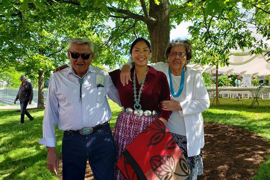 ALTTEXT Person at graduation posing with their grandparents.