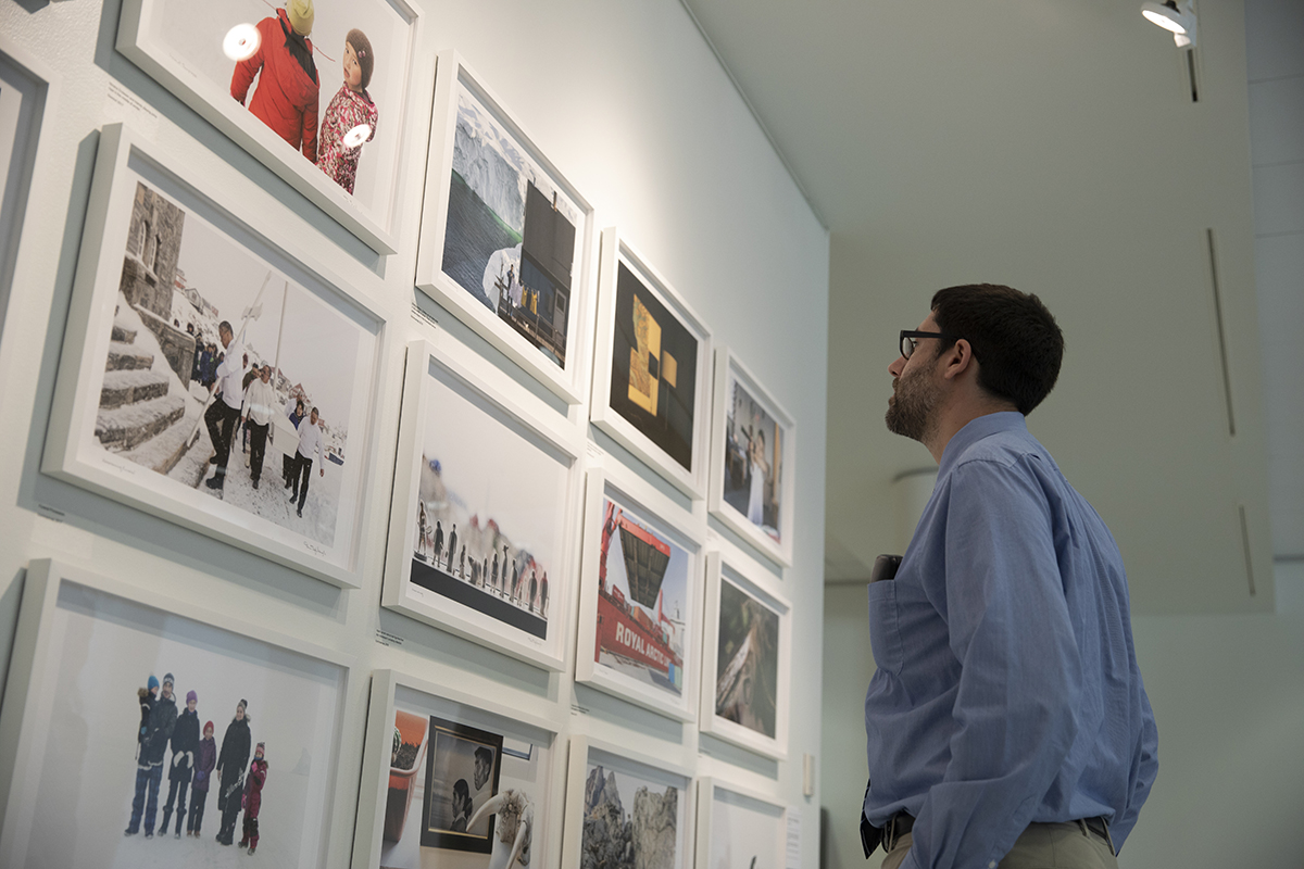 A person looks at a wall full of Denis Defibaugh's Greenland photos as they are displayed in University Gallery. The photo was taken as part of Denis Defibaugh's NSF grant.