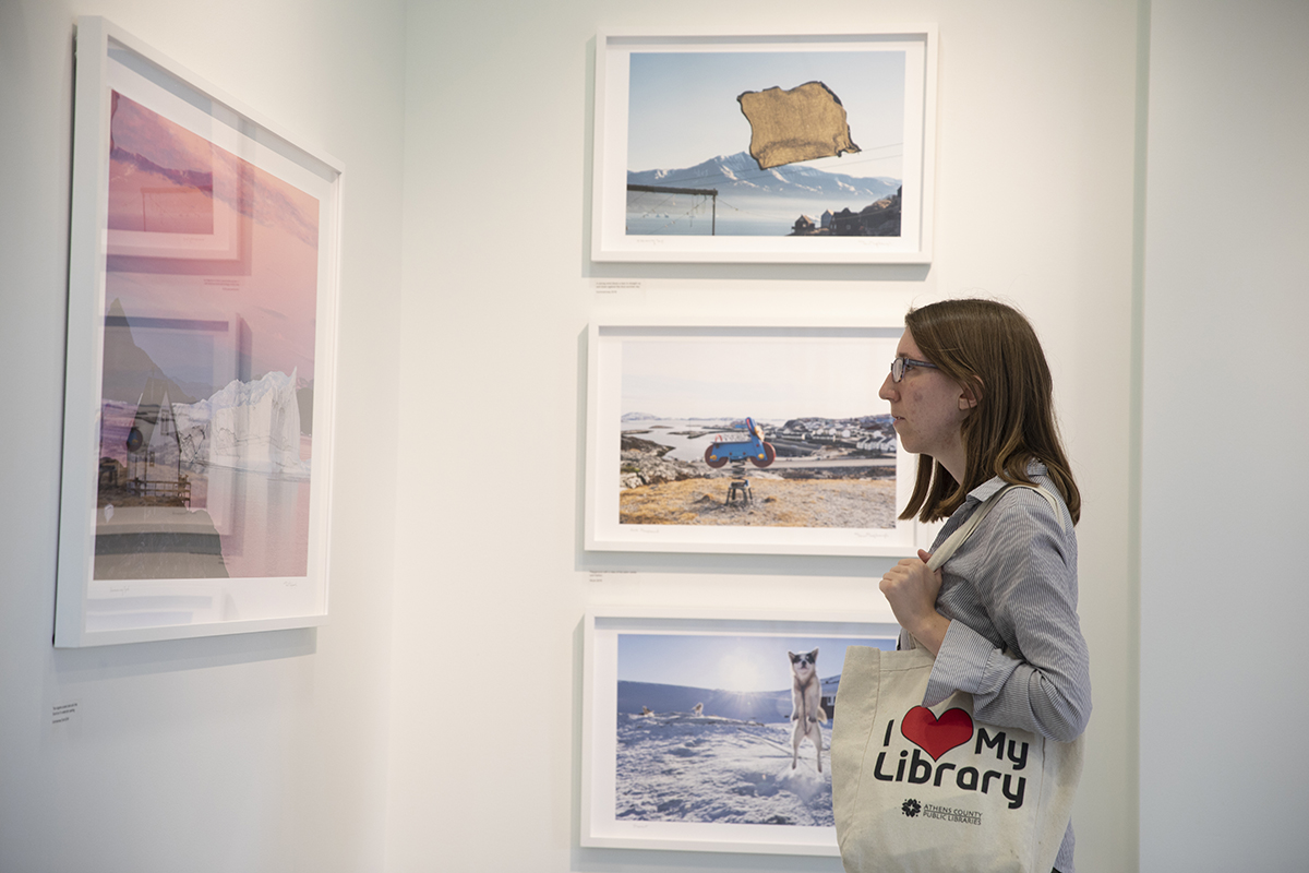 A University Gallery visitor closely observes a Greenland photo by Denis Defibaugh. The photo was taken as part of Denis Defibaugh's NSF grant.