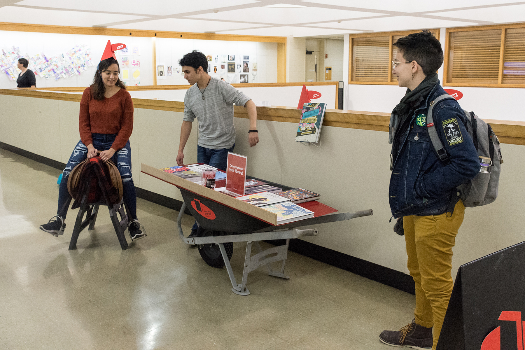 Students use a wheelbarrow and saddle to display books.