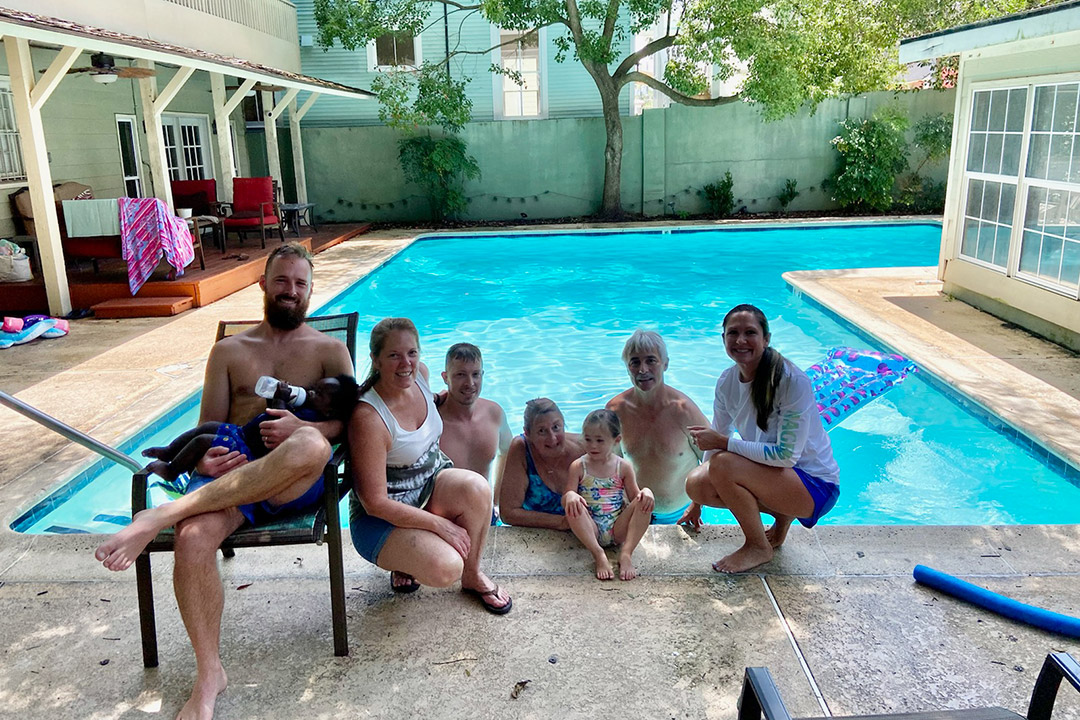 a family posing for a photo at the end of an inground pool.