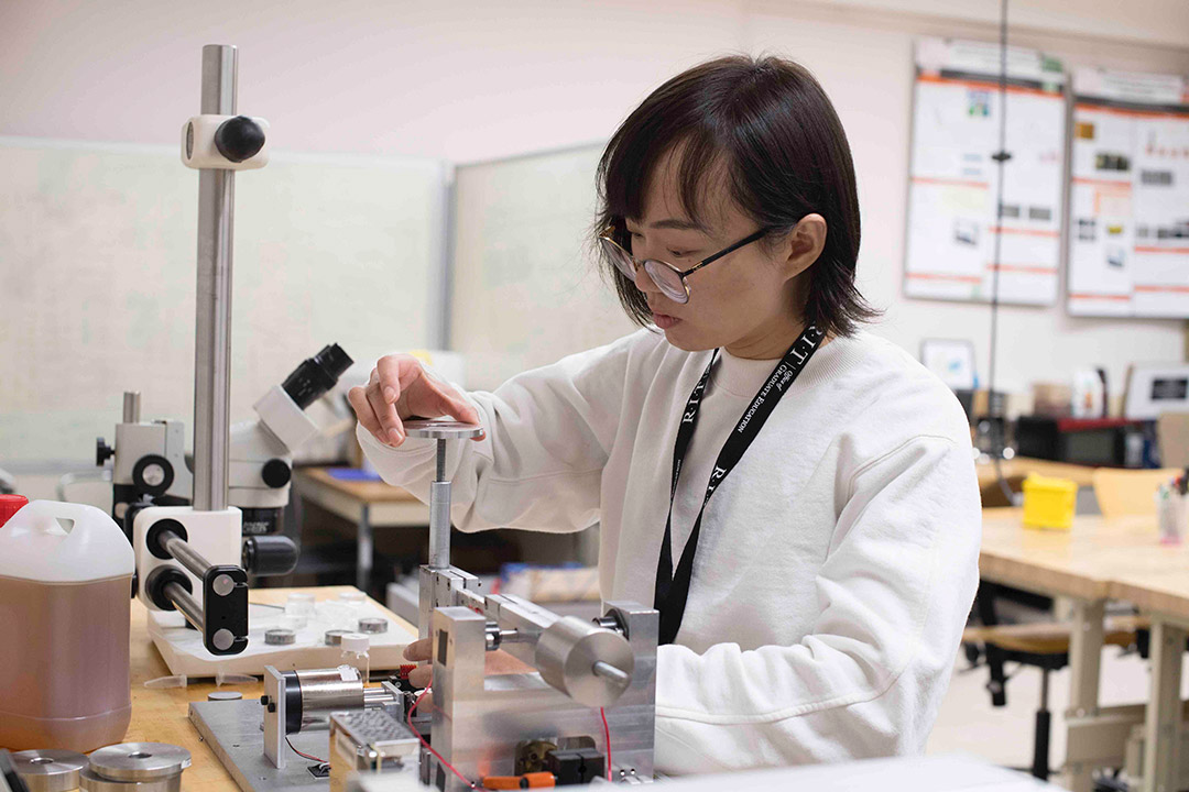 student wearing lab coat working with gear equipment.