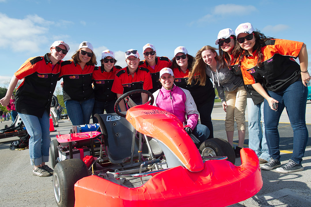 10 students standing around their electric race car.