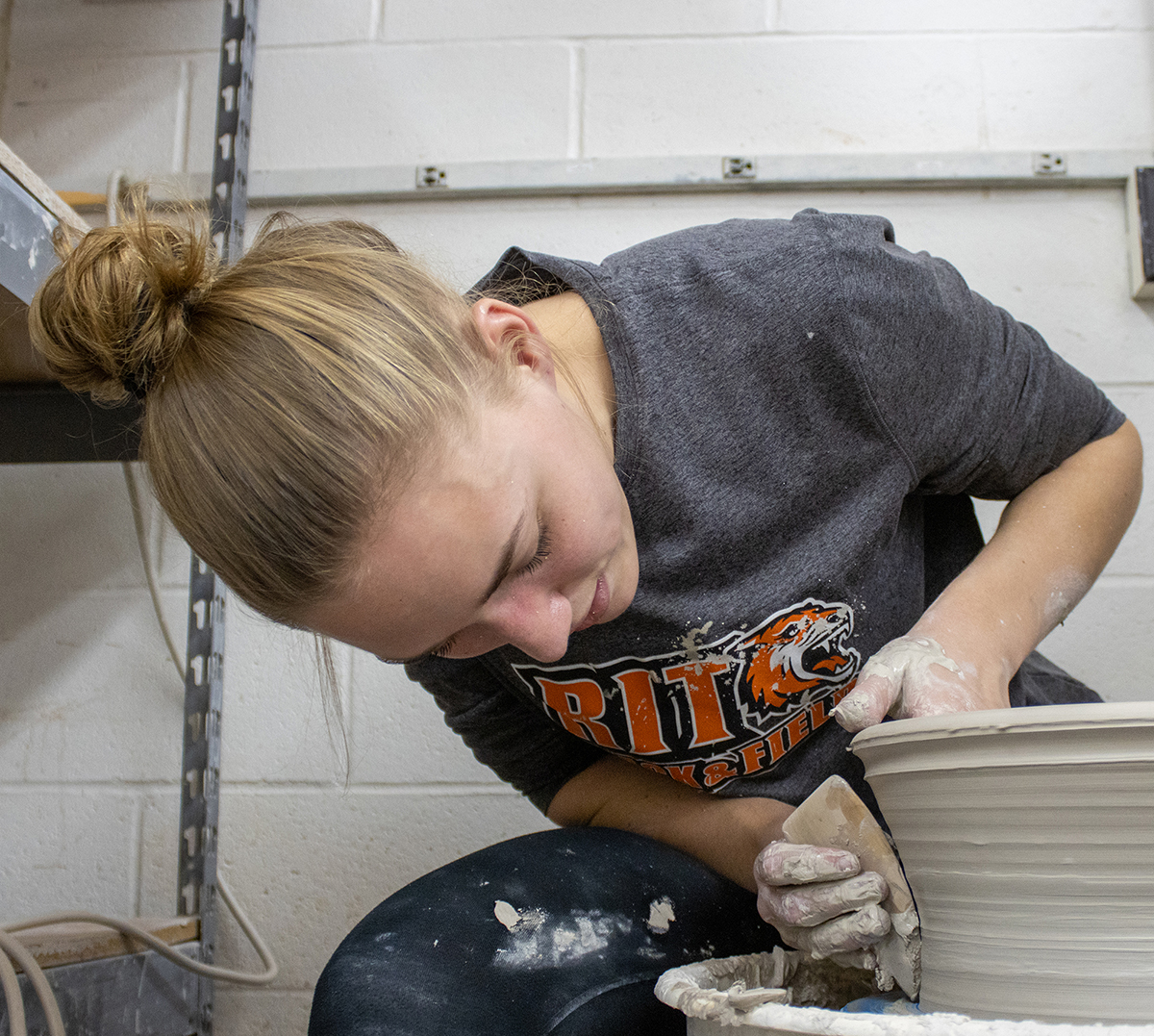 Marian Draper focuses on creating a large vessel on a potter's wheel.