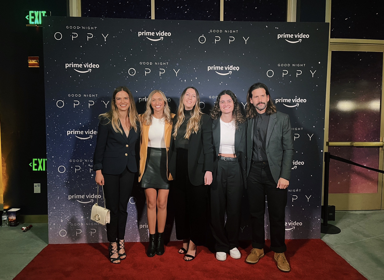 A group of people pose during a red-carpet premiere.