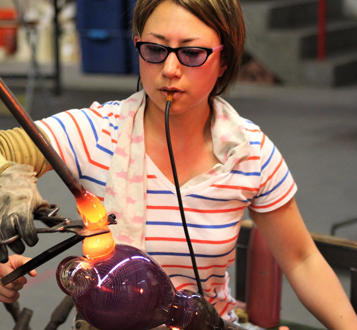 Aya Oki blows glass in a studio.