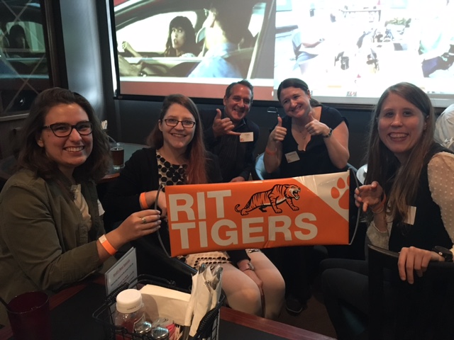 Students holding on a flag that says "RIT TIGERS".