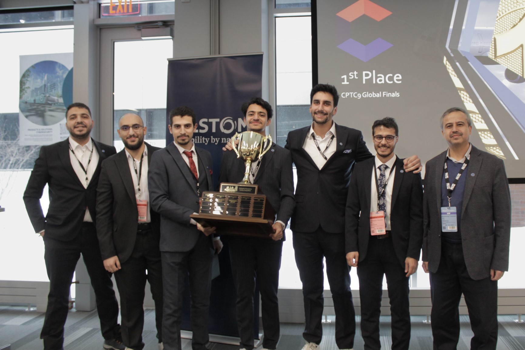 Group of seven people in suits with trophy.