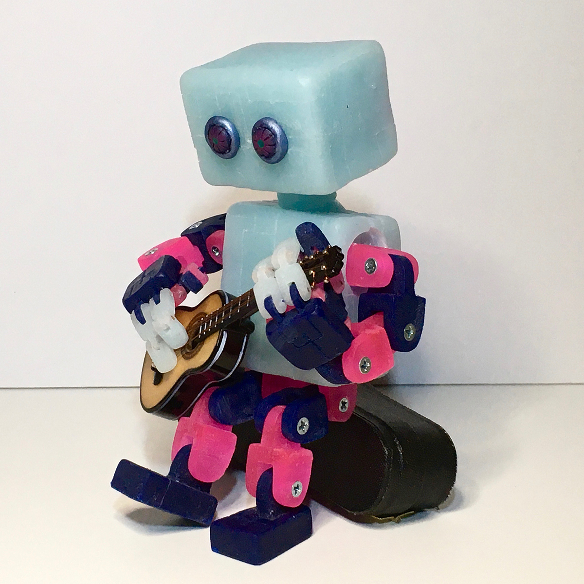 A toy robot sculpture plays a guitar.