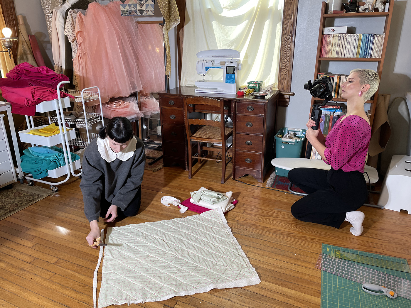 Julia Abbonizio takes video of Jenna Gagnier cutting fabric.