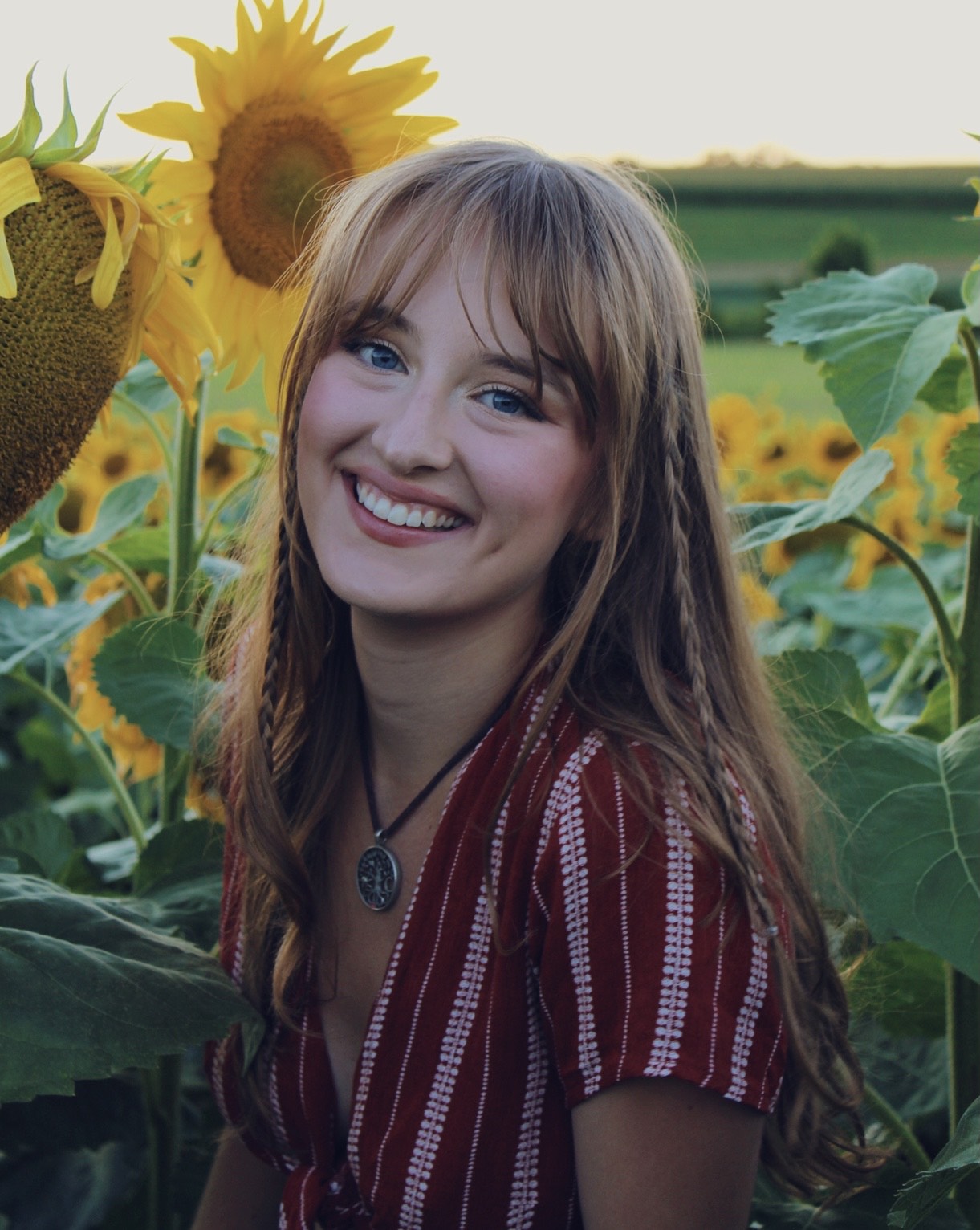 A headshot of Isabelle Anderson in a field of sunflowers.