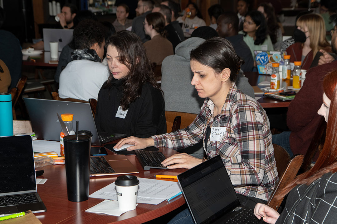 Two students sitting at table looking at their laptops.