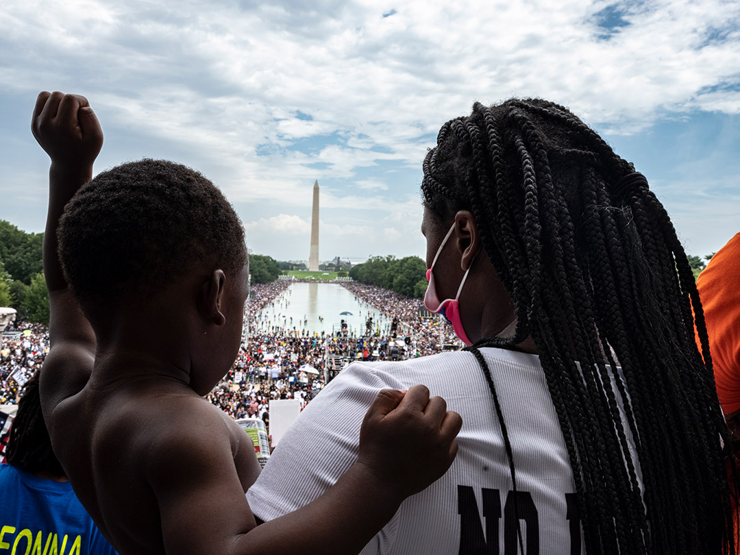 woman and child looking out at a crowd in front of the Washington Monument. 