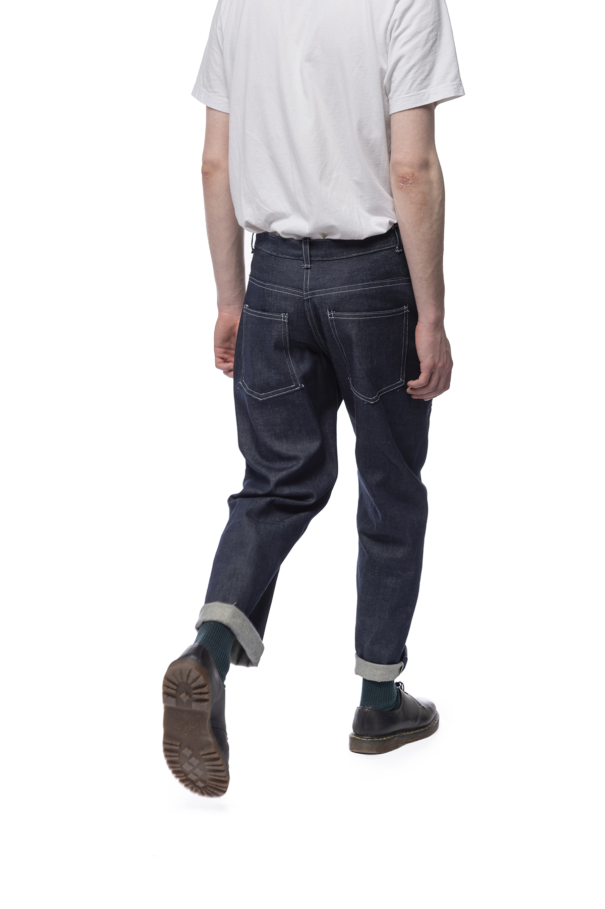 Functional clothing design of jeans that are rolled just above a model's ankles. 