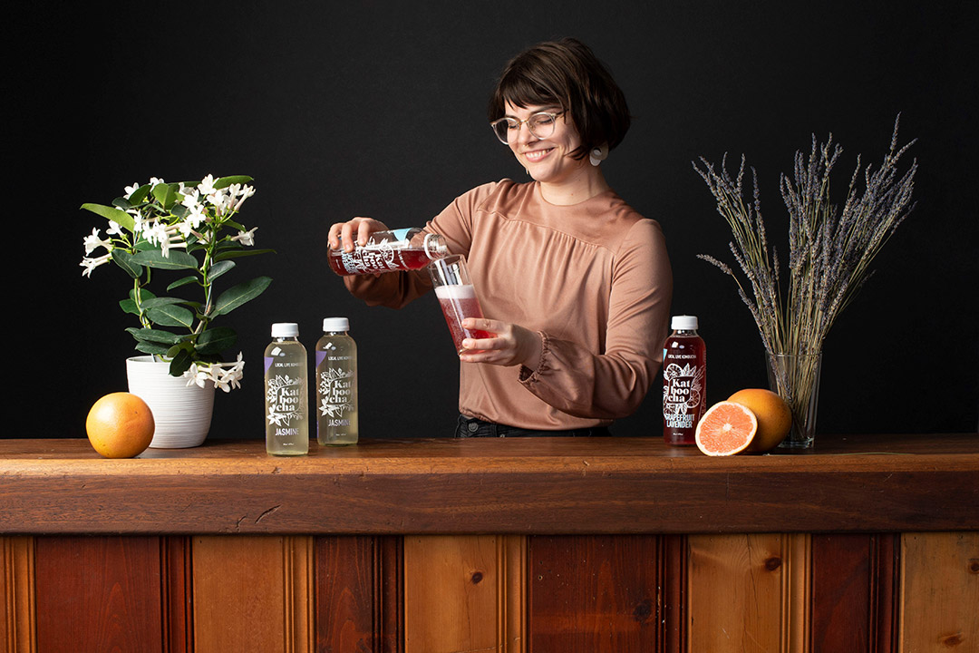 Woman pours beverage into glass.