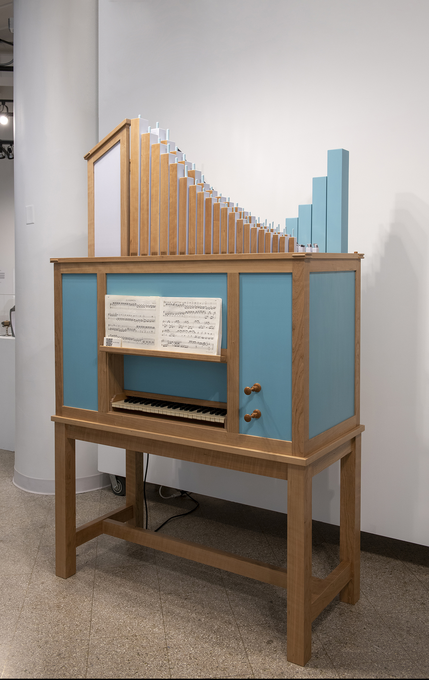 A handmade, wooden pipe organ in a gallery space.