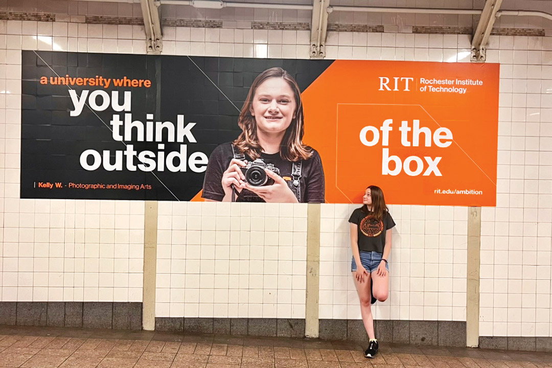 college student standing against a wall with an ad that features her picture.