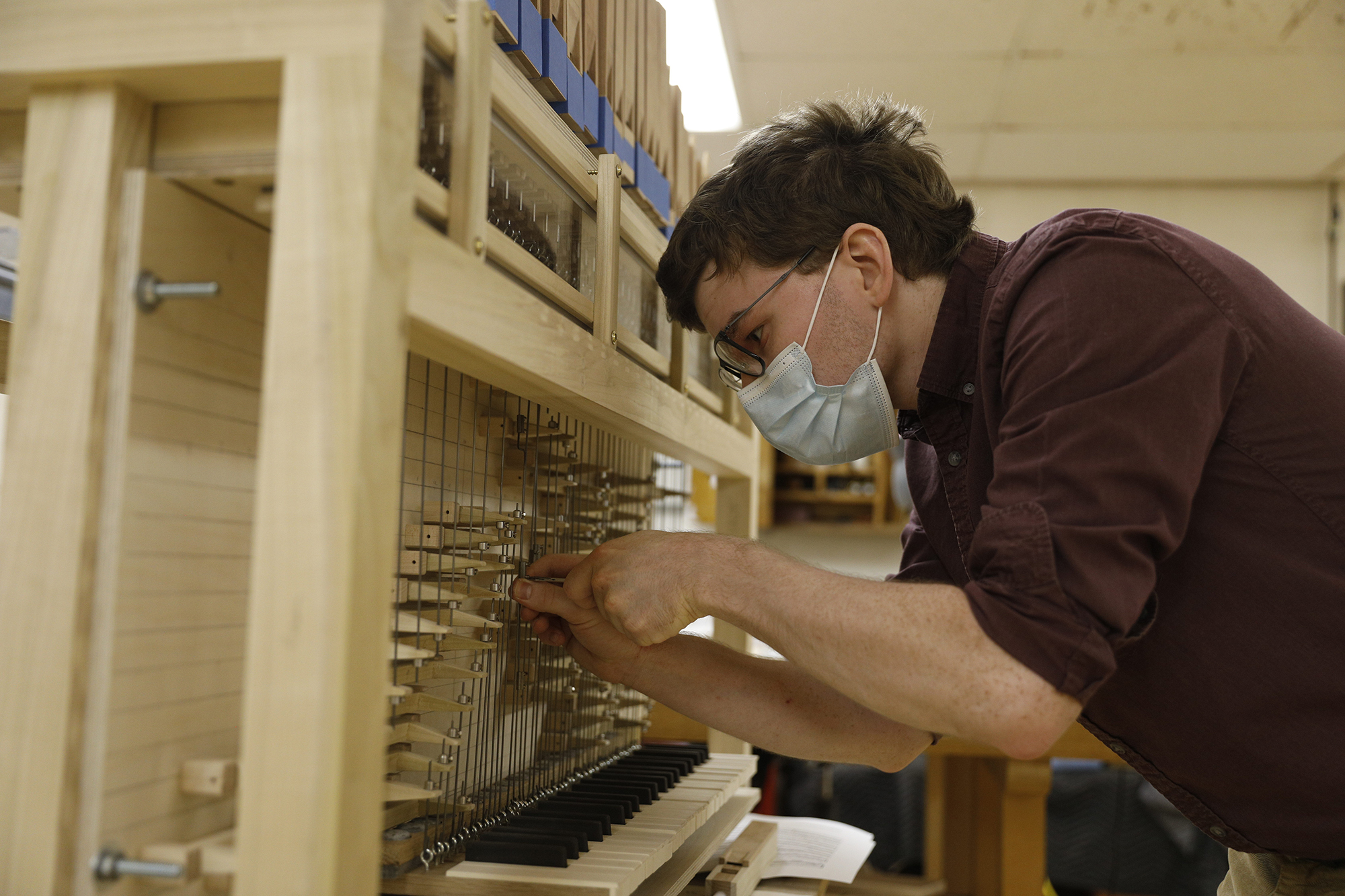 Kelly Cleveland uses a hand tool to adjust the mechanics of his pipe organ.