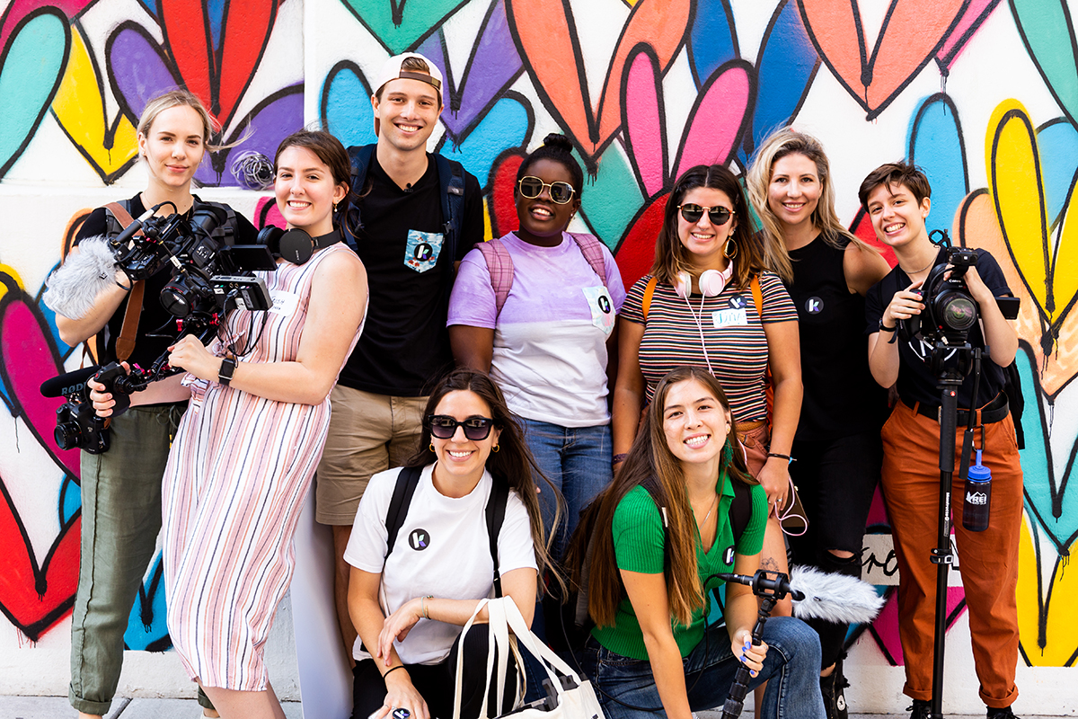 A group of people pose for a photo in front of a colorful wall.