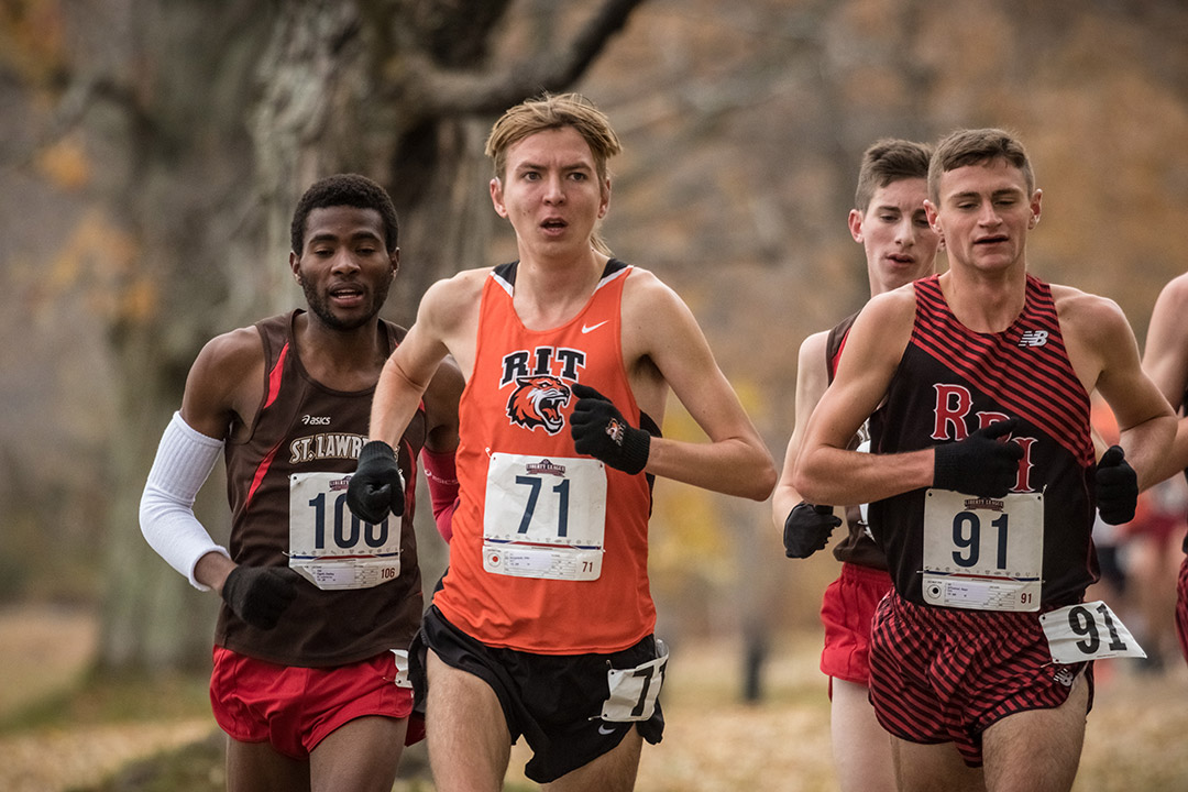 four track and field athletes running outdoors.