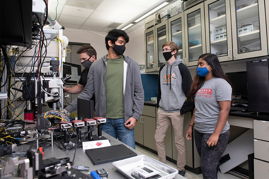 student researchers wearing masks and working in a lab.