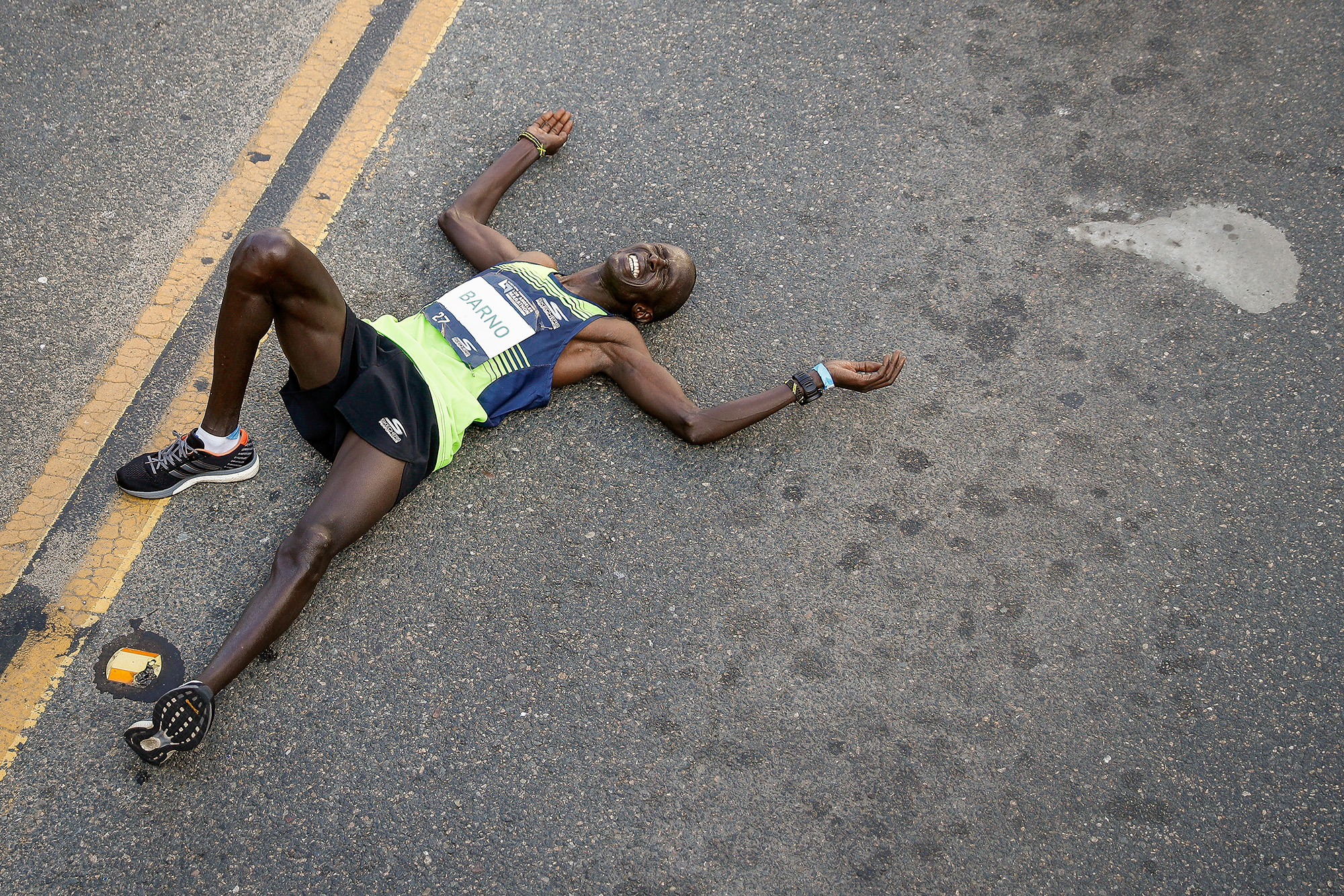 A runner lays down on pavement.