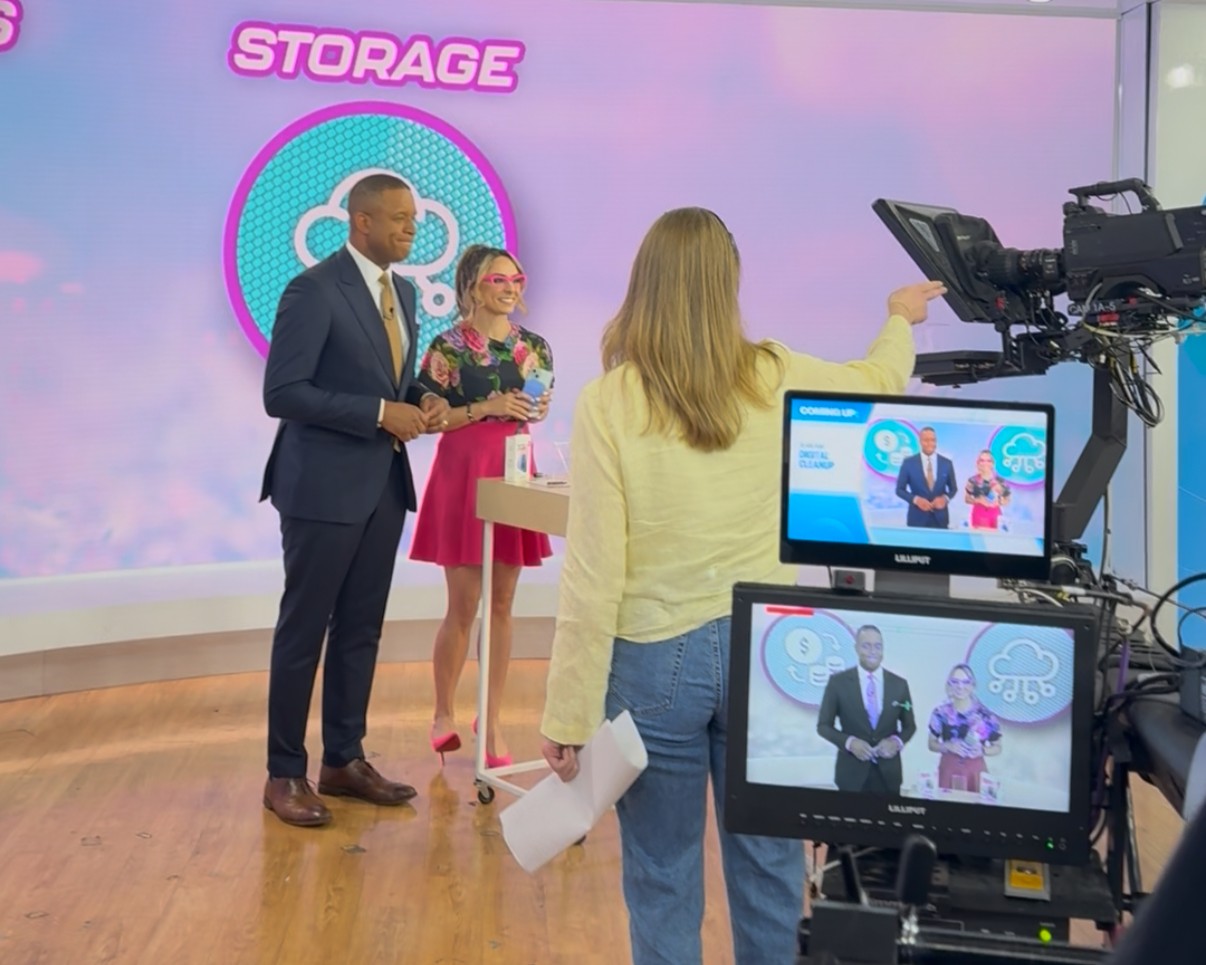 Three people stand on a TV studio set for the Today show. 