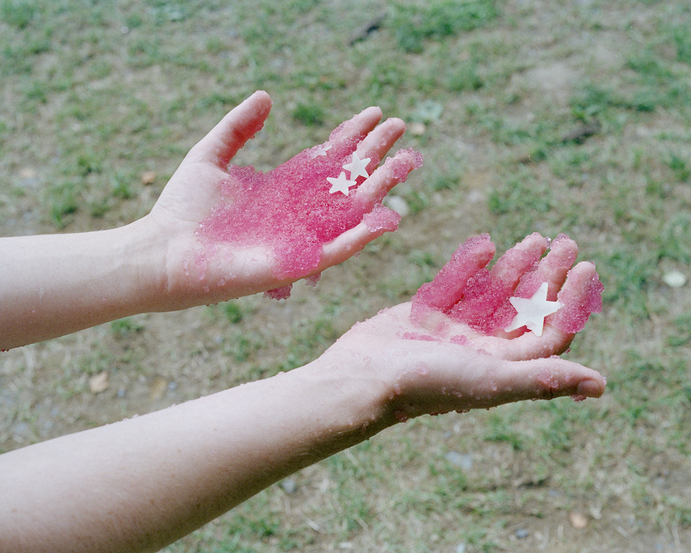 A photo of two hands holding a pink, glittery substance.