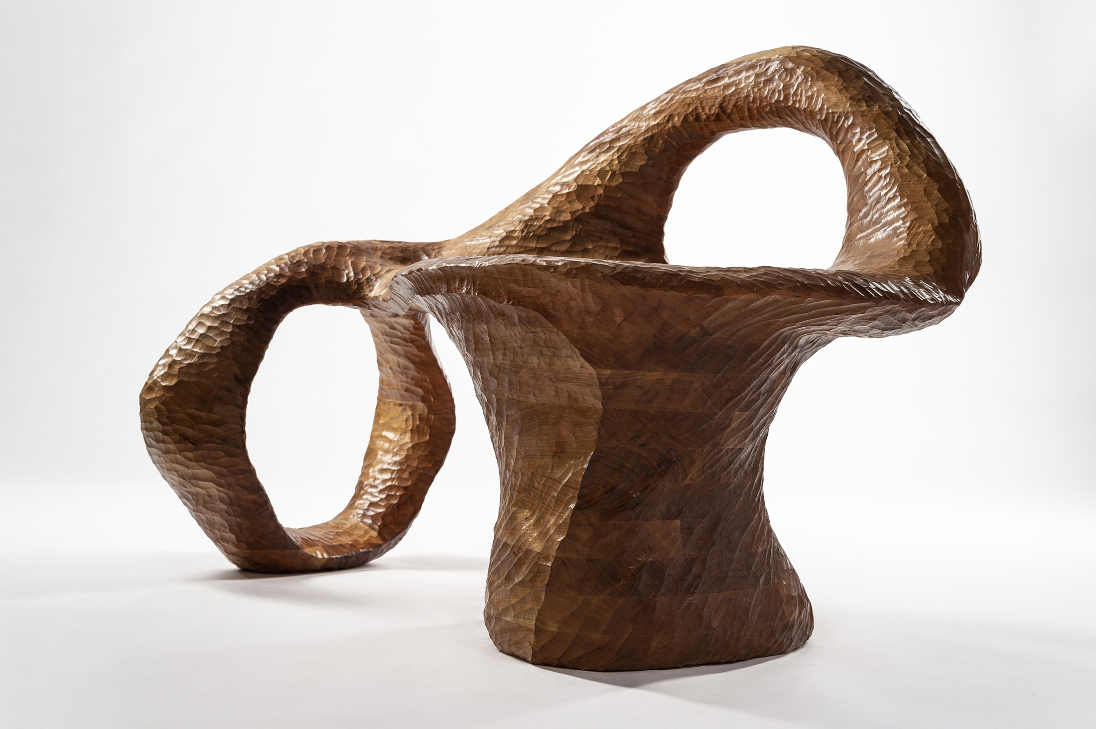 An abstract-shaped chair made of laminated cherry wood.