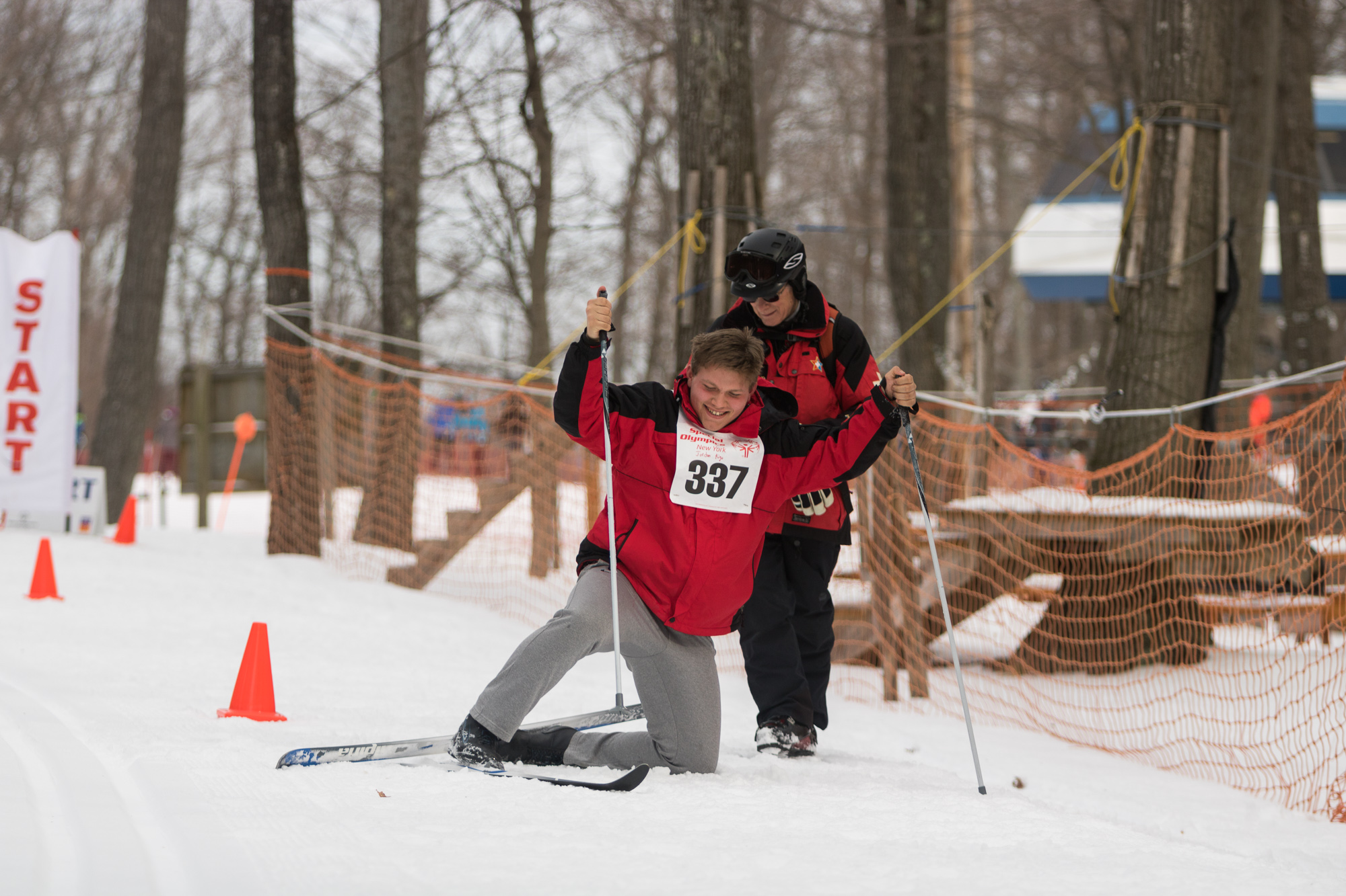 Emergency ski patrol Al Kraus helps Jordon Rigo back to his feet during his preliminary time trial for cross country skiing. Sports photography by Mariah Whitmoyer.