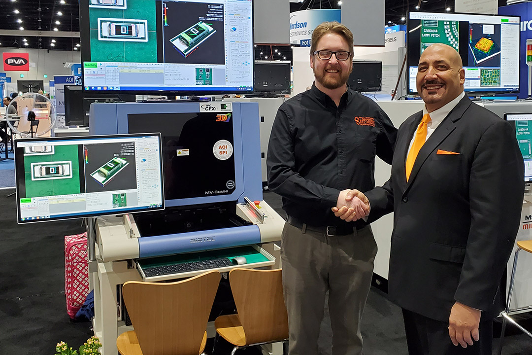 two man shaking hands in front of computer equipment display.