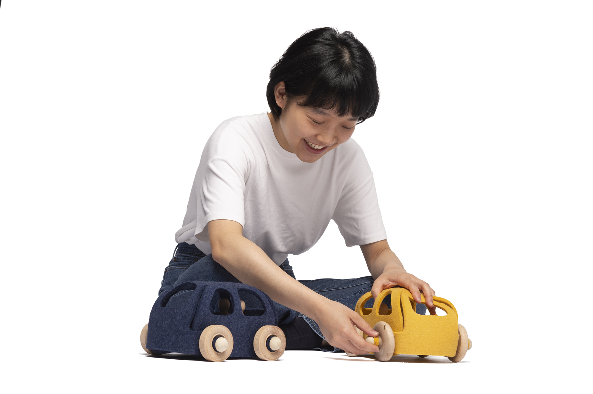 A person plays with toy cars made out of fabric and wooden wheels.