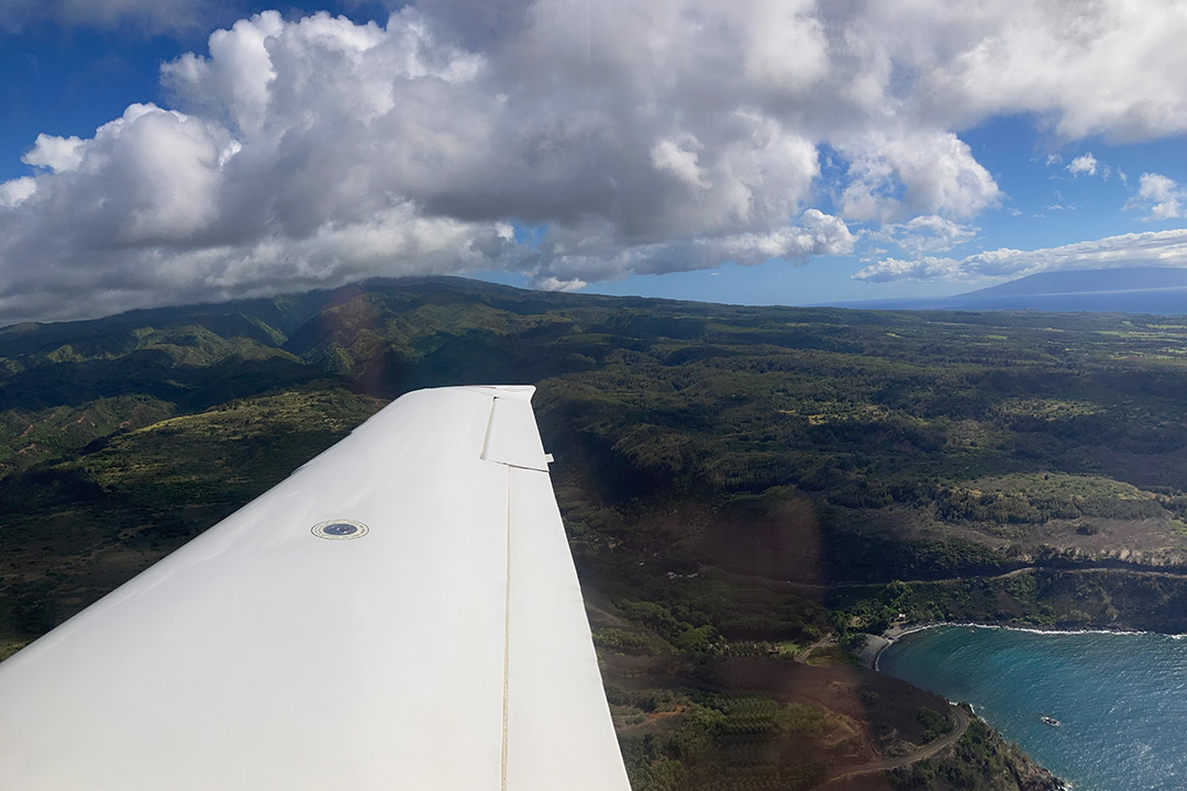 view from an airplane of the plane's wing, mountains, and a lake.