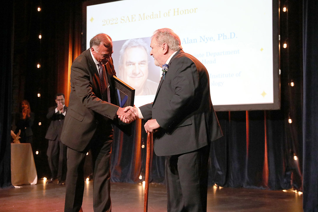 two people standing on stage shaking hands.