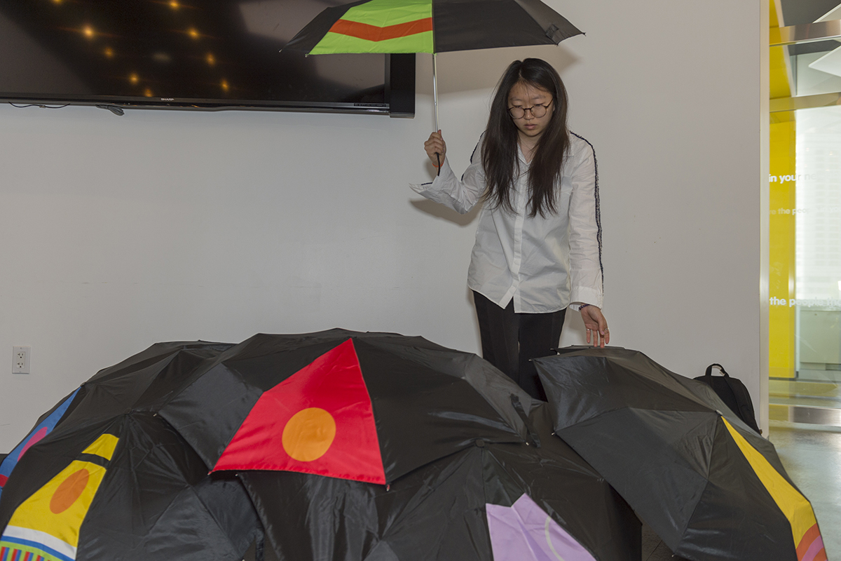 Sumin-Petal Oh stands beside — and with — her Sesame Street-inspired umbrella set.